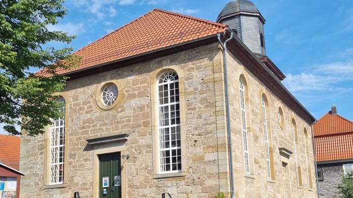 Altes Steinhaus mit grünen Tür und Uhr, rote Ziegeldächer, sonniger Tag