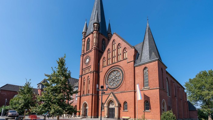 Große rote Backsteinkirche mit zwei Türmen und einem runden Buntglasfenster.