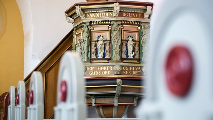En prædikestol med udsmykning og latinske indskrifter i kirke.