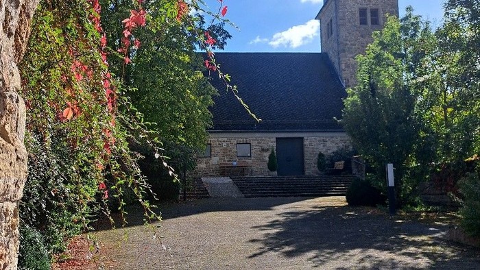 Steinweg, der zu einer Kirche mit einem Uhrturm führt.