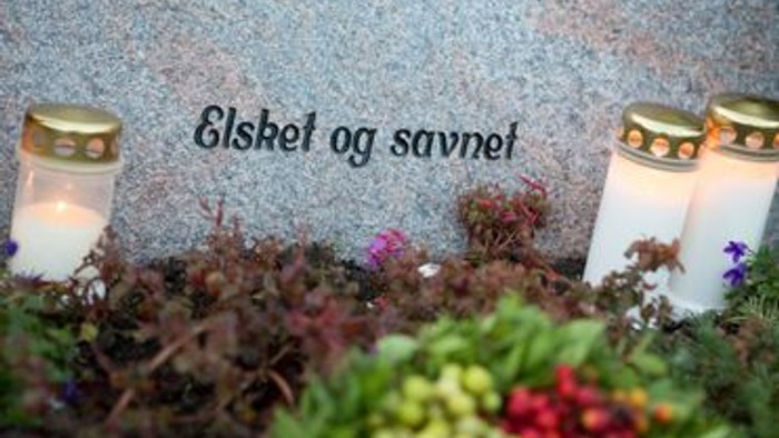 To gravsten med lysstaker og blomster