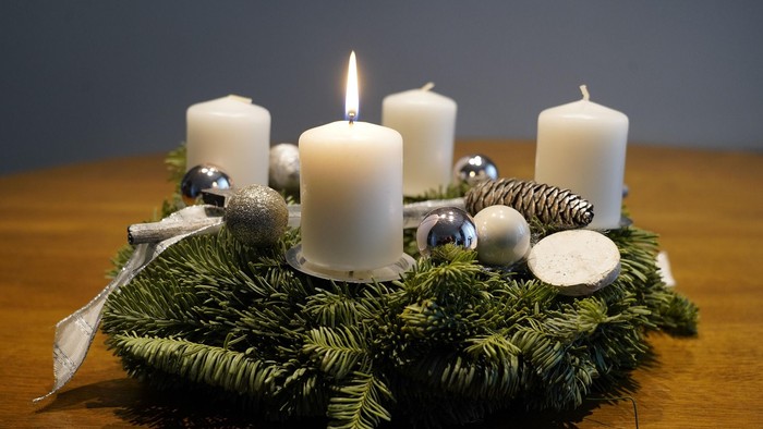 En juledekorasjon med lysende lygter og grønne grene på bord.