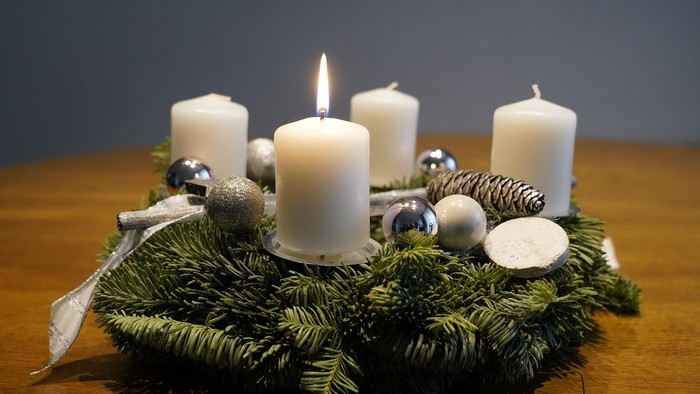 En juledekorasjon med lysende lygter og grønne grene på bord.