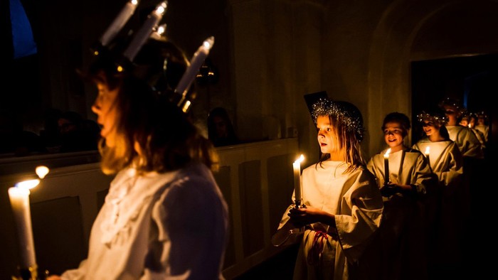 En gruppe børn med lysekøn i en mørk kirke.