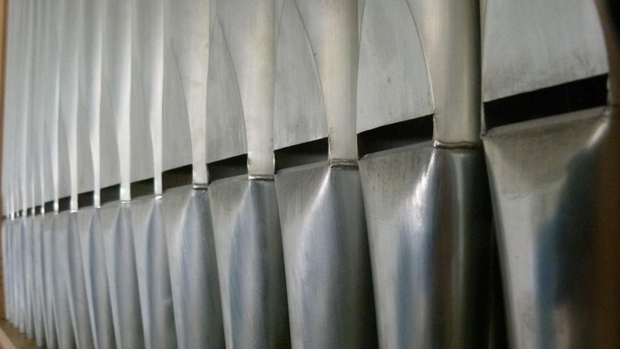 Auf einem Regal ordentlich in einer gebogenen, parallelen Reihe angeordnete Aluminiumrohre.