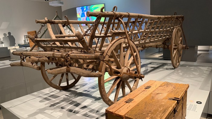 Antiker Holzwagen und Kiste in einer Museumsausstellung ausgestellt.