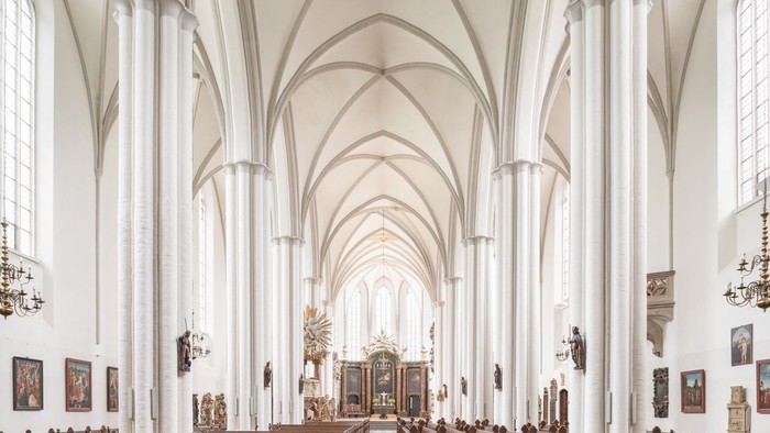 Großzügige, helle Kirchenhalle mit hohen Bögen und zahlreichen Bänken