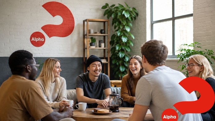 Eine vielfältige Gruppe von Menschen versammelte sich fröhlich um einen Tisch in einem gemütlichen Café mit Alpha-Branding.