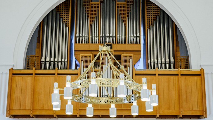 En stor orgel med guldfarvet lysestativ foran