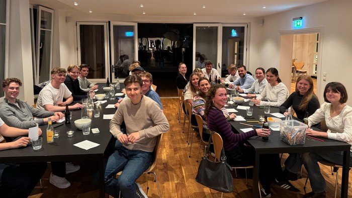 Gruppe af mennesker samlet til en formel middag eller møde med drinks og samtale i et hyggeligt lokale.