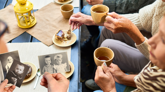 Die Leute versammeln sich um einen Tisch, teilen Tee und betrachten alte Familienfotos.