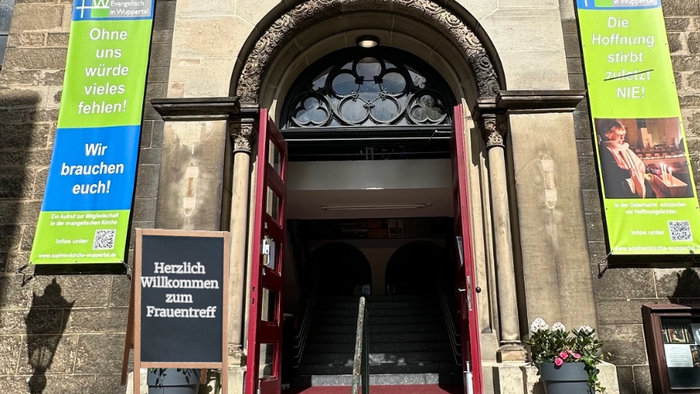 Eintritt zu einem einladenden Treffpunkt für Frauen mit deutschen Bannern und einer Treppe.
