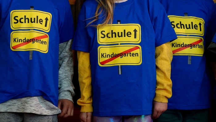Drei Kinder in blauen T-Shirts mit Aufdruck 