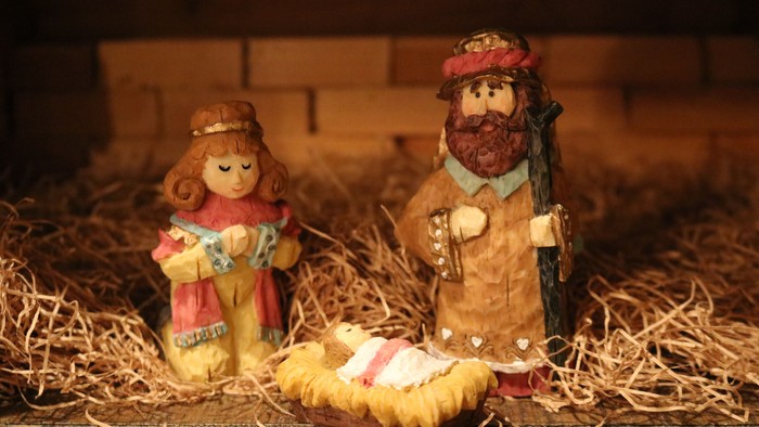 En lille nativity scene med tre figurer og en kuld.