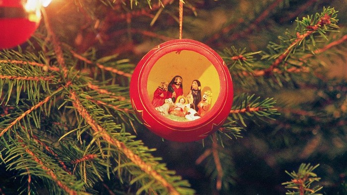 En rød glaskugle med en lille nativity-scene hænger på en juletree