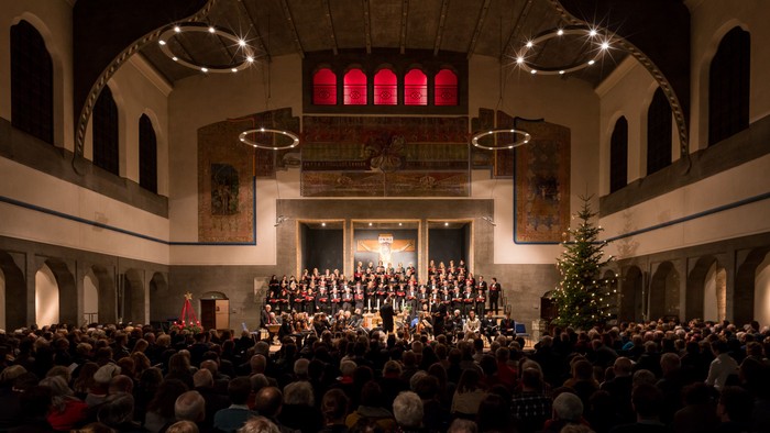 Große Menschenmenge bei einem Konzert in einer Kirche mit Weihnachtsbaum