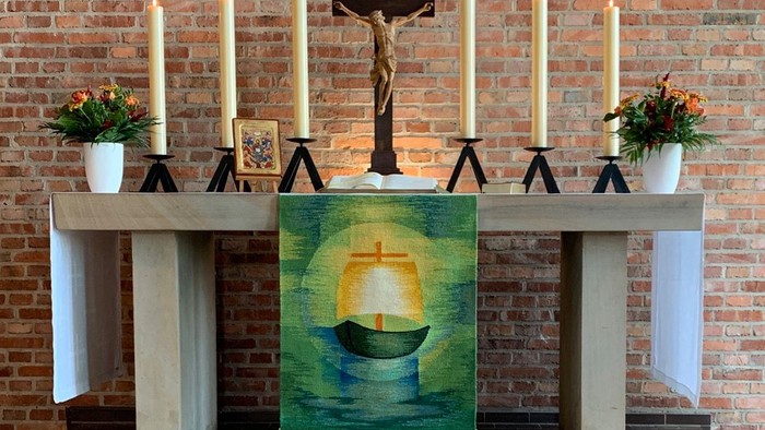 Bild zeigt eine Kirchenaltar mit Kreuz, Kerzen und Gemälde