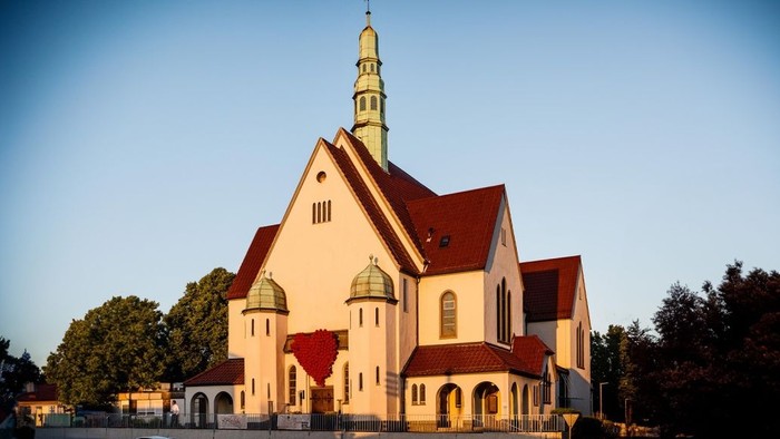 Eine markante Kirche mit rotem Dach und goldener Spitze vor klarem Himmel.
