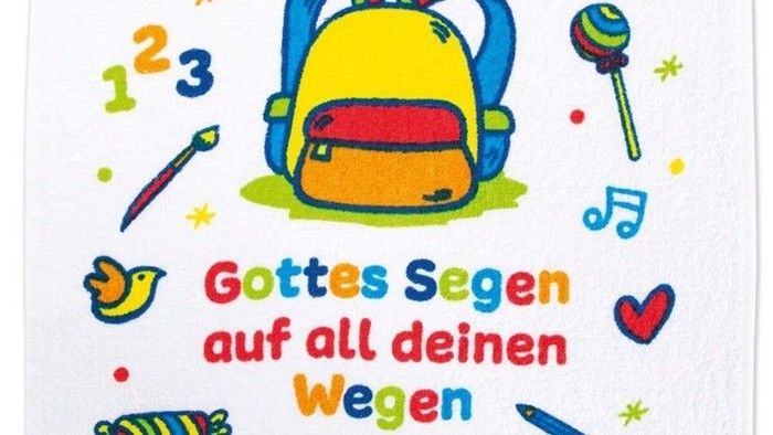 Bunte Handtuch mit schulbezogenen Segenswünschen und dem deutschen Spruch *„Gottes Segen auf all deinen Wegen“*, umgeben von Bildungs-Symbolen.