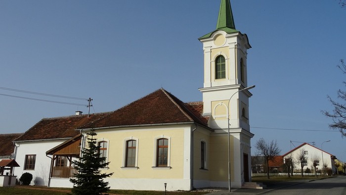 Kleine Kirche mit hohem Turm und grünem Dach in ländlicher Gegend