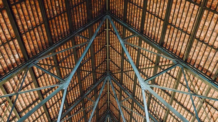 Symmetrischer Blick auf den historischen Dachstuhl des Ulmer Münsters mit blauen Stahlträgern und rötlichen Dachziegeln.