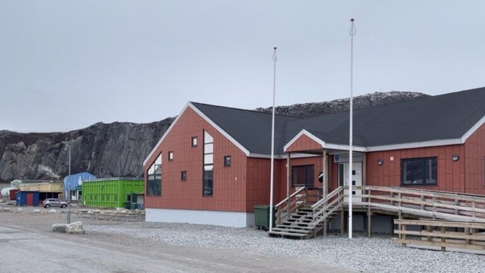 Landsbybygninger med røde tage og ramper med en klippefyldt, bjergrig baggrund.