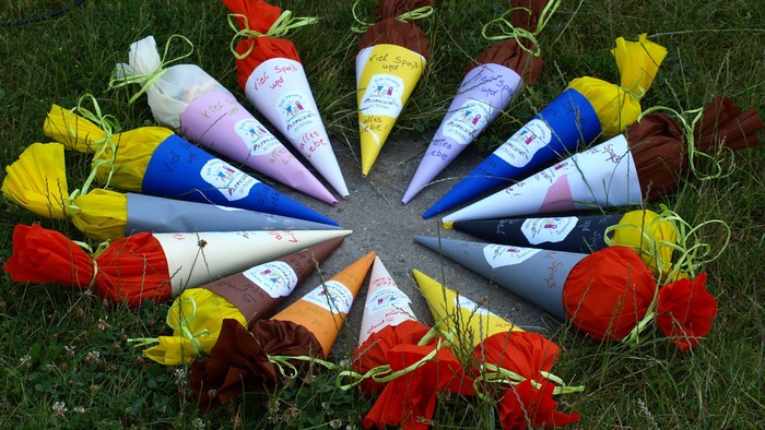 Schultüten liegen im Kreis im Gras