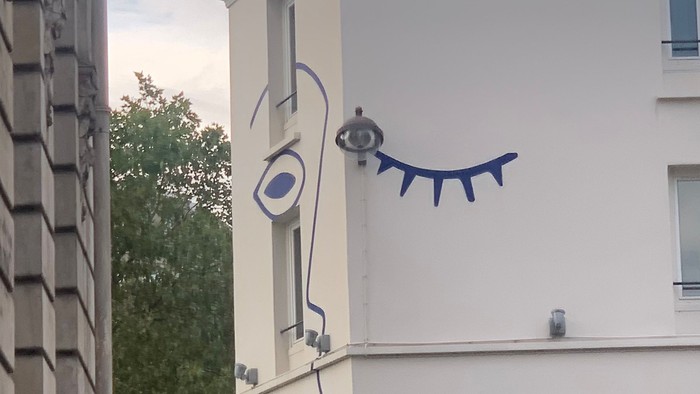 En blå kattefigur på væggen af et hvidt hus.