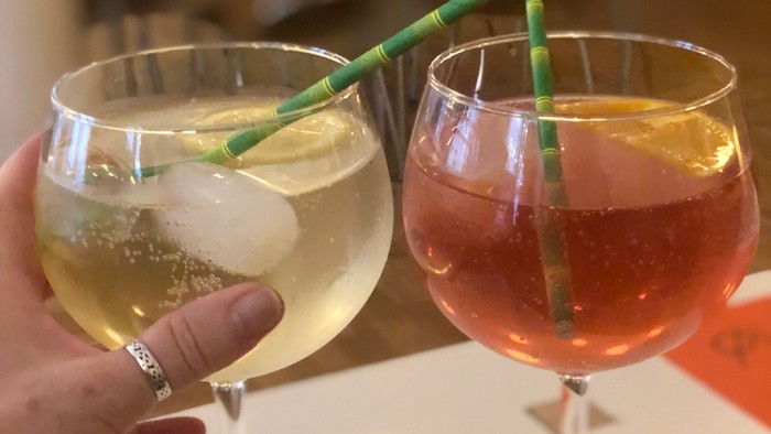 En hånd holder to glas med drikke med grønne stammer.
