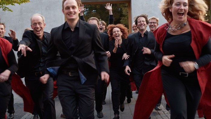 Eine Gruppe von Menschen in formeller Kleidung rennt fröhlich.