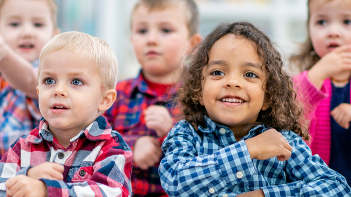 Einige Kinder sitzen in einer Reihe und lächeln in die Kamera.