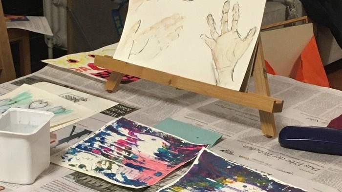 Ein Tisch mit verschiedenen Kunstwerken und Materialien, darunter ein Pinsel und ein Easel.