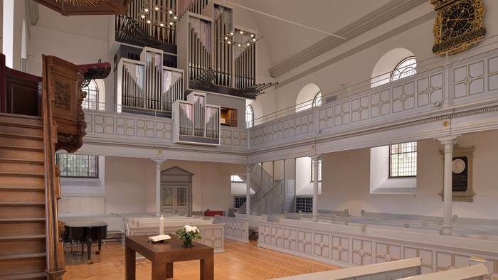 Elegante Kircheninnenausstattung mit einer großen Pfeifenorgel, hölzernen Kirchenbänken und klassischen architektonischen Details.
