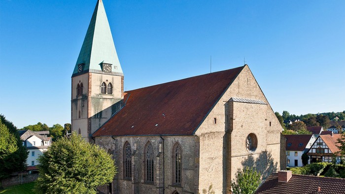 Historische Steinkirche mit hohem Turm und rotem Ziegeldach in einem malerischen Dorf.
