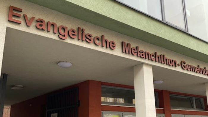 Evangelische Melanchthon-Gemeinde Gebäude mit rotem Eingang und großen Fenstern