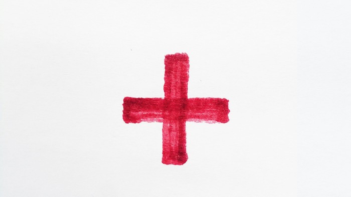 Ein einfaches rotes Kreuzsymbol auf einem schlichten Hintergrund.