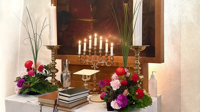 Alter med rød-lyserøde blomster og syv lys