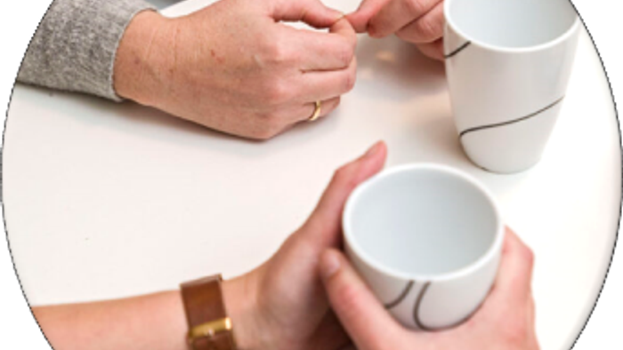 To personer holder hvide kopper med sorte designs.