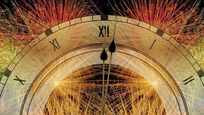 Ziffernblatt einer Uhr kurz nach 0 Uhr mit Feuerwerk