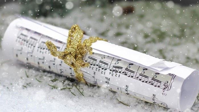 Notenblatt, im Schnee eingerollt, mit goldener Stern-Dekoration.