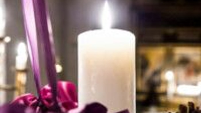Elegant hvid lysestage omgivet af lilla blomster i en blødt oplyst, festlig opsætning.