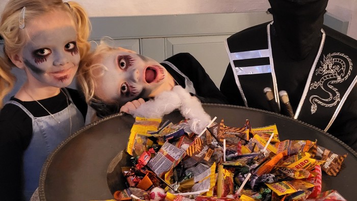 To børn med horror-makeup og en maskeret person med chokolade.