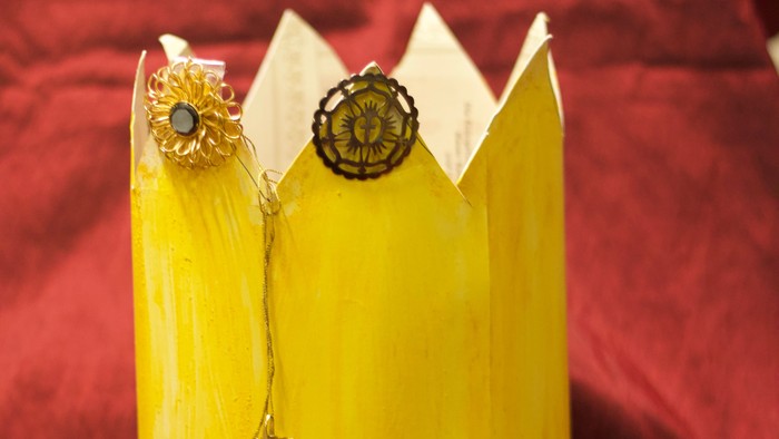 Gelbe Krone mit Edelsteinen auf rotem Stoff