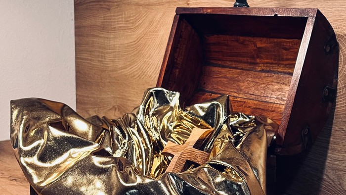 Goldene Stiefel vor einer Holztruhe