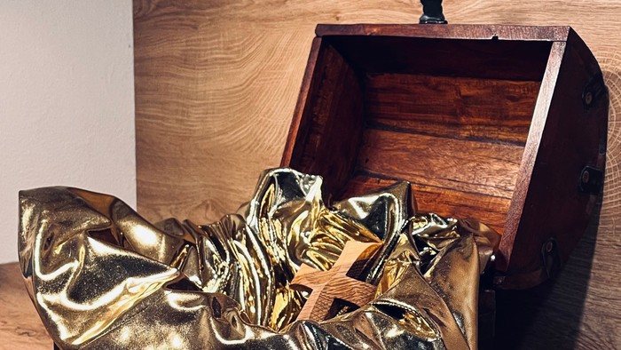 Goldene Stiefel vor einer Holztruhe