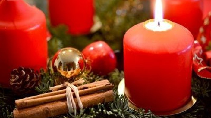 Weihnachtliche Dekoration mit roten Kerzen, Tannenzapfen und Zimtstangen