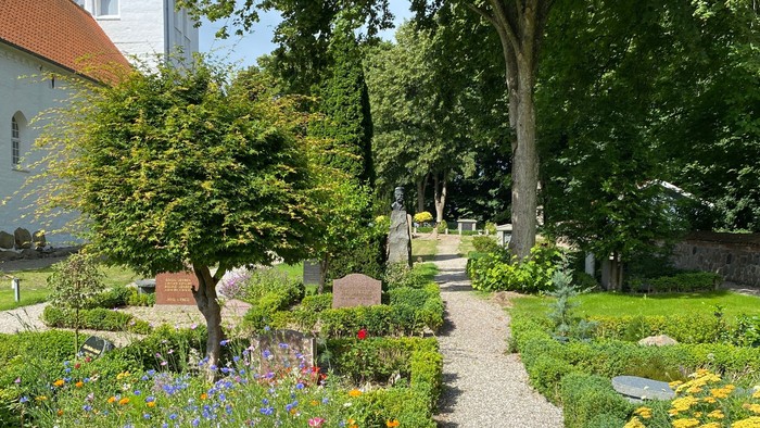 En smuk have med blomster og en sti gennem træerne