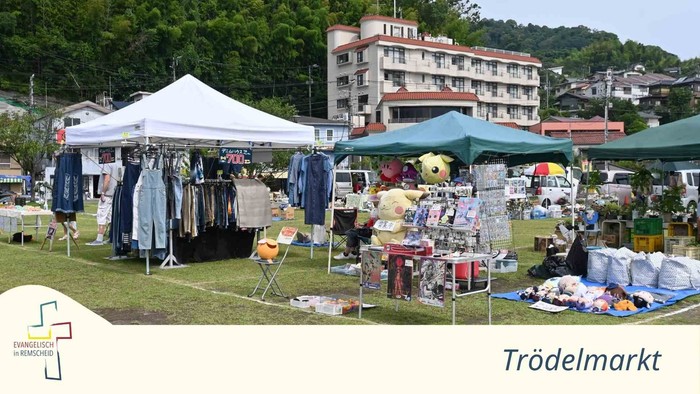 Flohmarkt im Freien mit verschiedenen Ständen, die Kleidung, Haushaltsartikel und Sammlerstücke unter Zelten verkaufen.