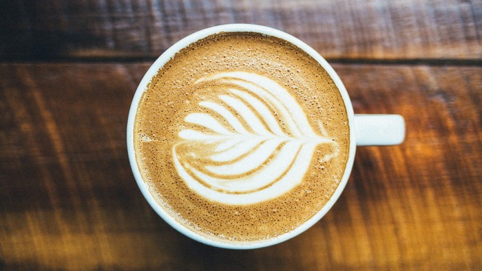Ein Cappuccino in einer Tasse auf einem Holztisch.