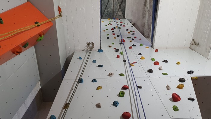 Blick von unten nach oben auf die Kletterwand in der Paul-Gerhardt-Kirche Altona mit zahlreichen Griffen.